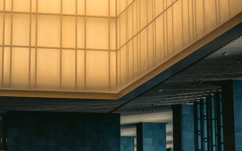 Hotel lobby with a backlit lattice ceiling and stone columns